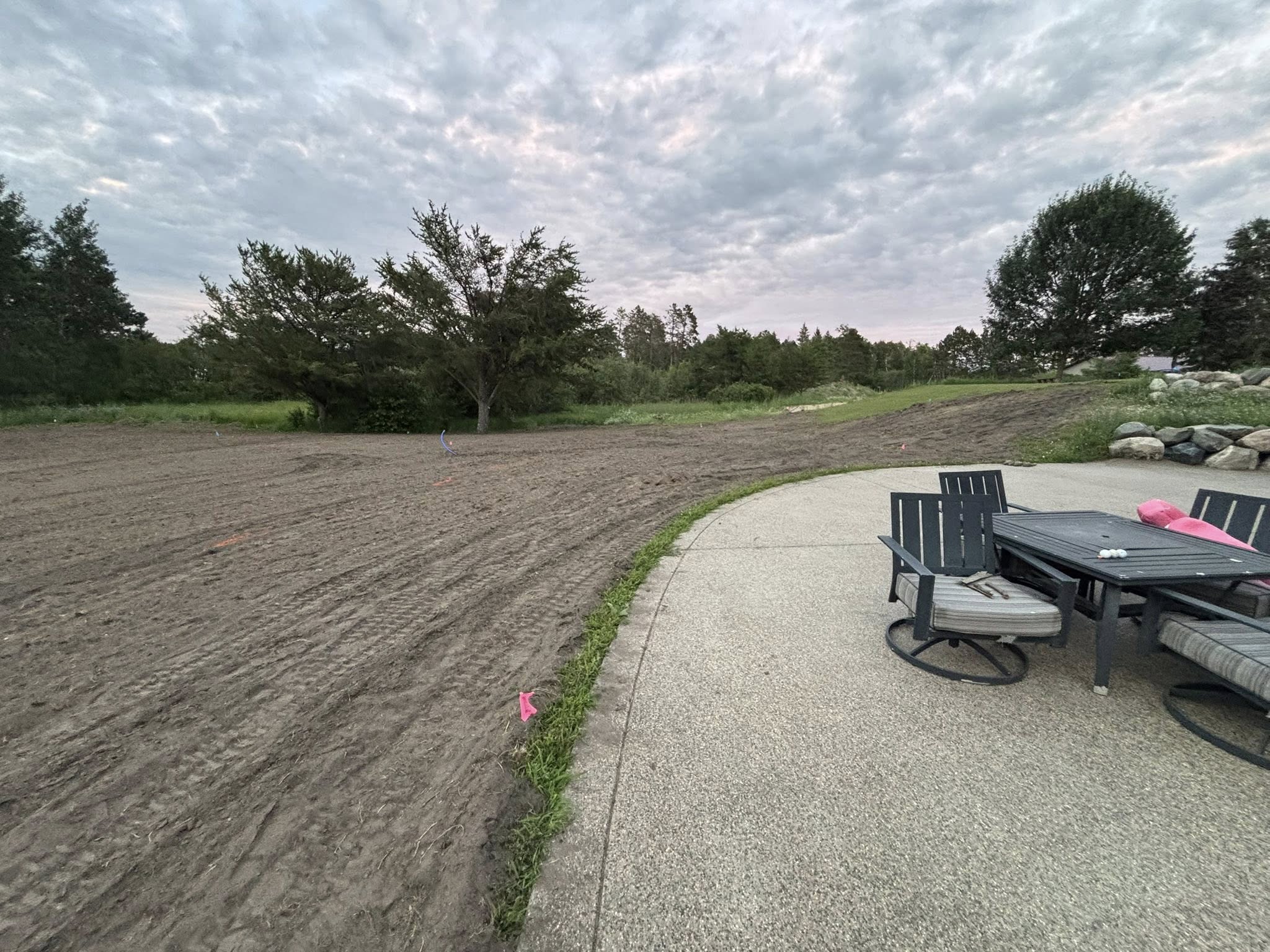 Graded backyard with smooth dirt next to lakeside patio