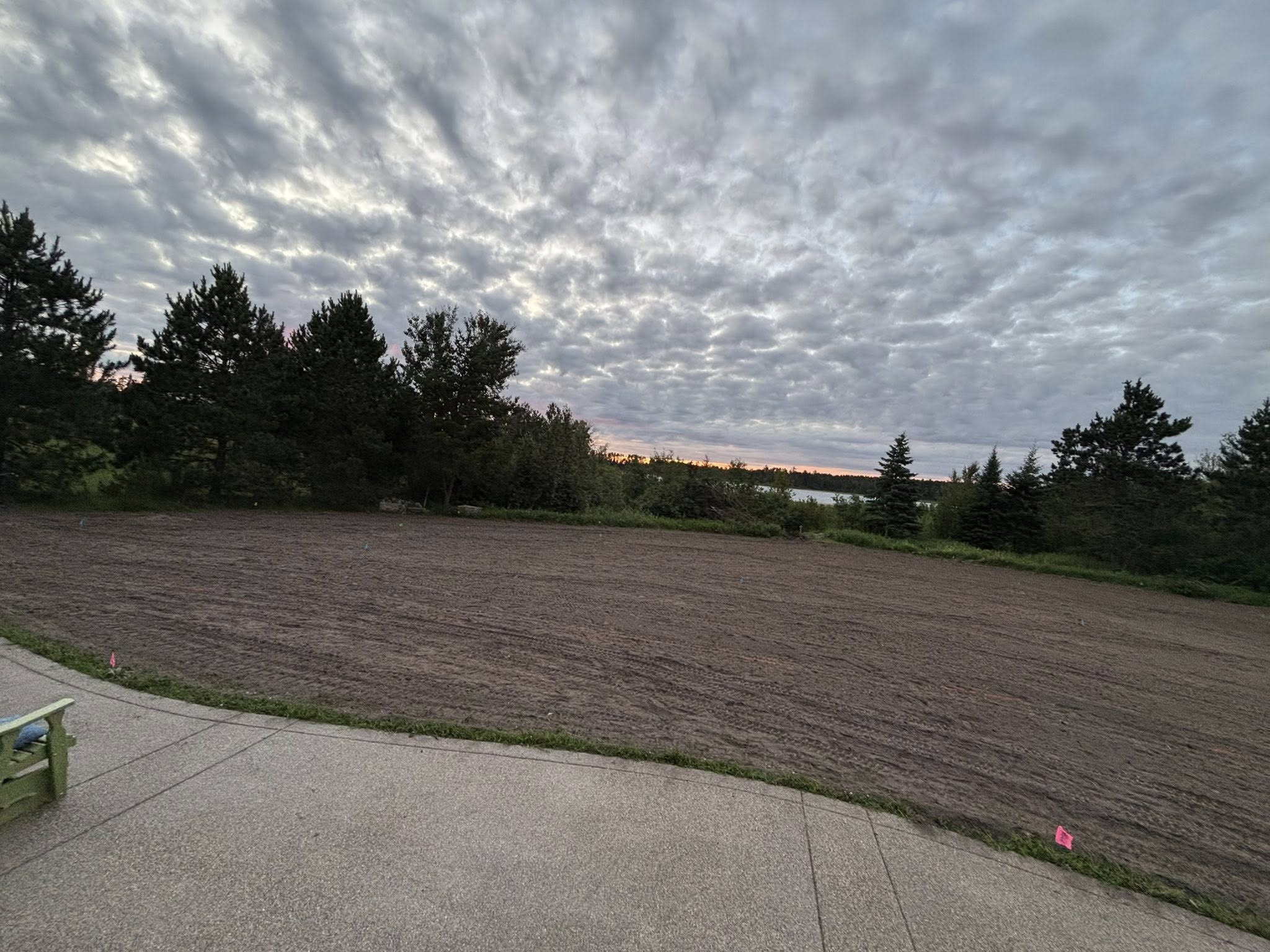 Wide view of freshly graded yard at sunset with lake in background