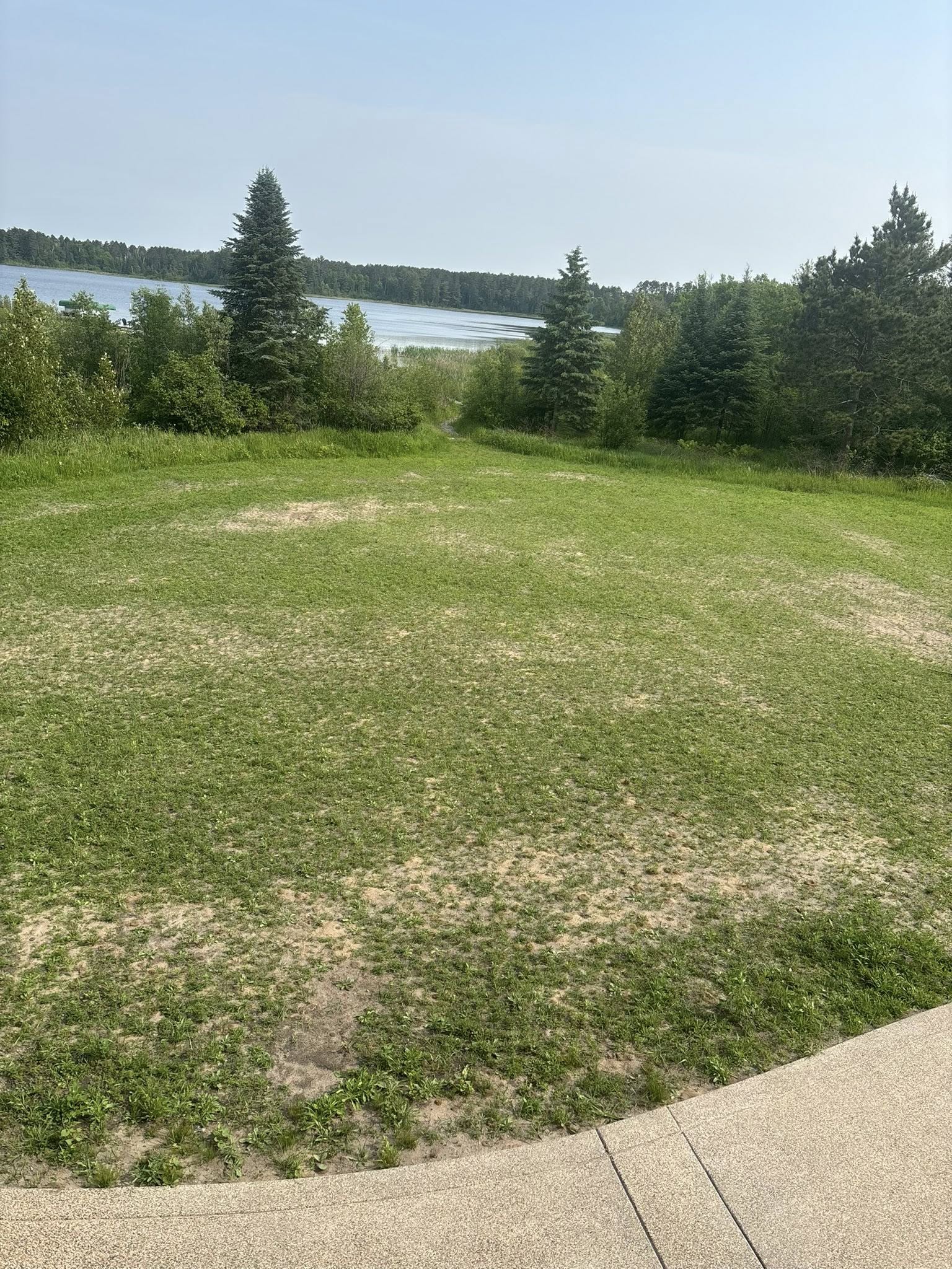 Lush green grass yard finished after grading work, lake in background